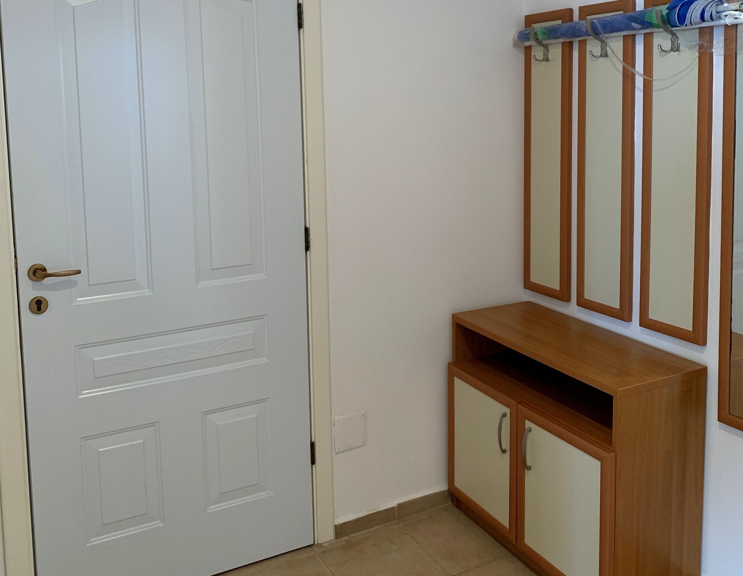 A white door with a keyhole, a wooden cabinet with two doors, and a mirror with a wooden frame on the wall.