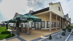 A building with a covered outdoor seating area and a sign reading "Carlsberg 1847 Copenhagen." - Hotel Graal (gmina Klaj)