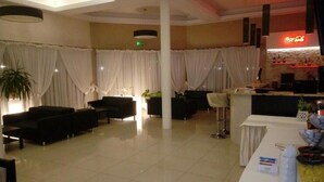 A hotel lobby with black sofas, a reception desk, and a Coca-Cola sign. - Hotel Graal (gmina Klaj)