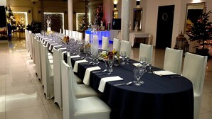 A long dining table set with chairs, a Christmas tree, and a decorative wall mural. - Hotel Graal (gmina Klaj)
