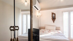 Un dormitorio con cama, televisor, espejo y candelabro.