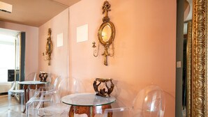Una habitación con sillas transparentes, una mesa redonda y espejos de pared decorados.