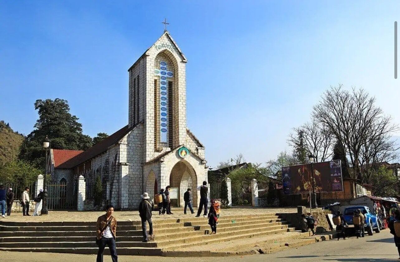 Una iglesia con un campanario alto y una cruz en la parte superior.