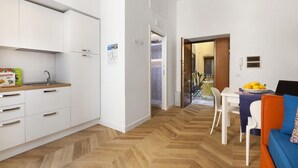 Una cocina compacta con armarios blancos, encimera de madera y suelo con estampado en espiga.