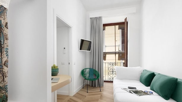 Una habitación de hotel moderna con cama, escritorio con ordenador, televisor y balcón con vistas.