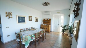 Comedor con una mesa redonda, sillas, un aparador de madera y una puerta.