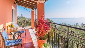 Un balcón con vista al mar, una mesa con sillas y una planta en maceta.