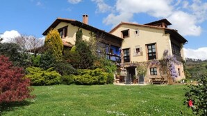 A two-story house with a garden in front. - Heredad de la Cueste (Llenín)