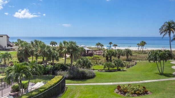 Um resort com vista para o oceano, palmeiras e uma praia.