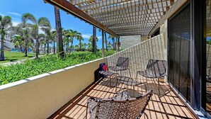 Een balkon met zitplaatsen buiten, uitzicht op palmbomen en een gebouw op de achtergrond.