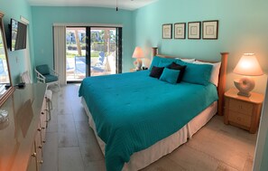 A bedroom with a large bed, a chair, a desk, and a TV. - Cozy Gulfview 2Bed/2Bath Condo (Sarasota)