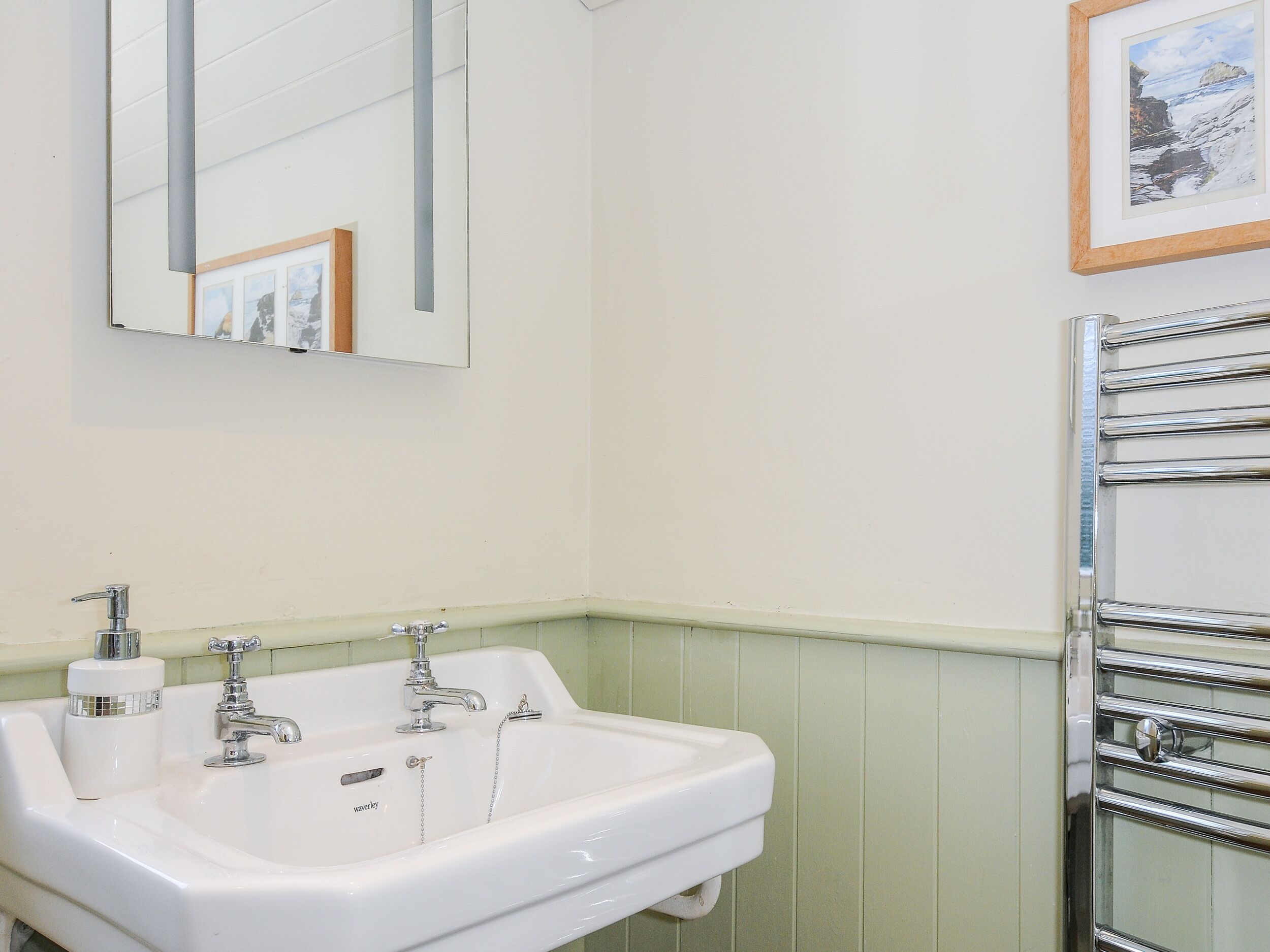 A bathroom with a white sink, chrome faucet, and a mirror above it.