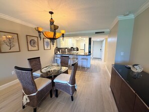 A dining area with wicker chairs, a glass table, and a hanging light fixture.