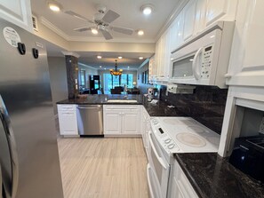 A modern kitchen with white cabinetry, a built-in oven, a microwave, and a dishwasher.