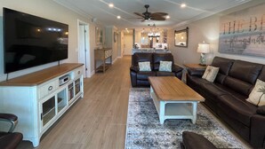 A spacious living room with a flat-screen TV, a leather sofa, a wooden coffee table, and a patterned rug. - Watch the sunset from you screened in lanai in this 2bd/2ba Condo (Sarasota)