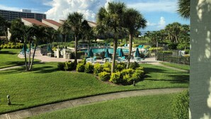 A resort with a swimming pool, palm trees, and a view of a building in the background. - Lovely Beach front 2Bd/2Bath Condo (Sarasota)