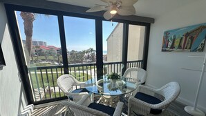 A balcony with a glass table, white wicker chairs, and a ceiling fan. - Enjoy beautiful sunset views (Sarasota)