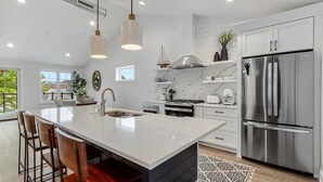 Una cocina moderna con una isla grande, electrodomésticos de acero inoxidable y una decoración en blanco y negro.