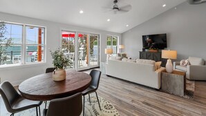 Una sala de estar moderna con un sofá, un televisor y un comedor con una mesa y sillas.