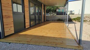 Enjoy the seamless transition between indoor and outdoor spaces in this modern outdoor area with a flat wooden deck and glass door.