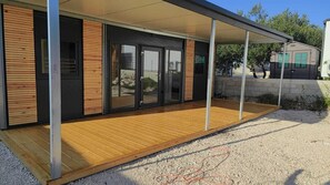 Guests can enjoy the covered outdoor area with a wooden deck and paved space.