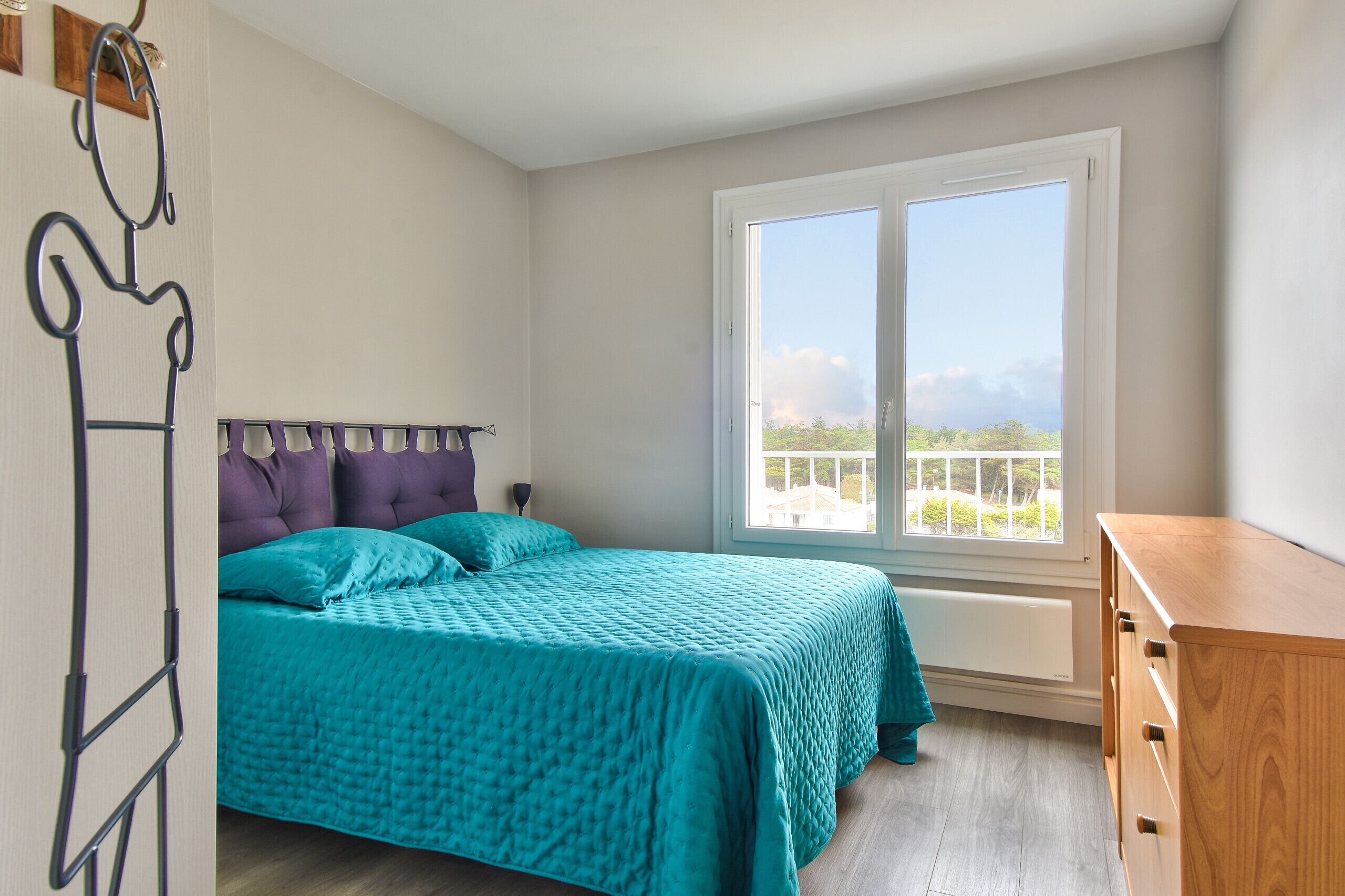 Un dormitorio con cama, ventana y cómoda.