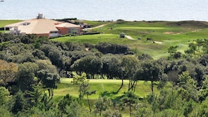 Golfkenttä, jossa on klubitalo, ja jota ympäröi tiheä metsä. Taustalla näkyy vesistö.