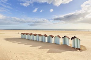 A beach with a row of striped beach huts.