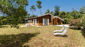 Una casa moderna con un patio, dos sillones y una mesita.