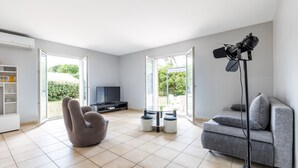 Una sala de estar moderna con un sofá gris, un sillón reclinable, una mesa de centro de vidrio y una lámpara de pie.