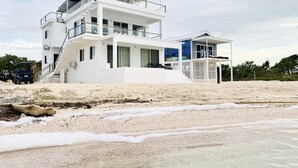 A modern multi-story beachfront property with a prominent staircase leading to the upper levels.