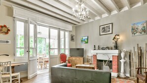 A spacious living room with a large sofa, a television, and a fireplace. - 150m from Betey Beach, house for 6 (Andernos-les-Bains)