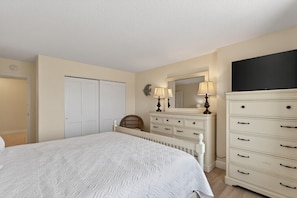 A bedroom with a bed, a dresser, a mirror, and a wardrobe.