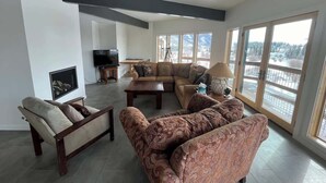 A spacious living room with a fireplace, large windows, and a modern design. - Cliff House - Newly remodel home with amazing view (Crested Butte)
