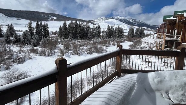 A snowy mountain landscape with a wooden balcony overlooking the view. - Cliff House - Newly remodel home with amazing view (Crested Butte)