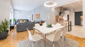 A modern living space with a dining area, kitchen, and a grey sofa with yellow cushions. - The HostMaster Cosmopolitan Downtown Scent (Αθήνα)
