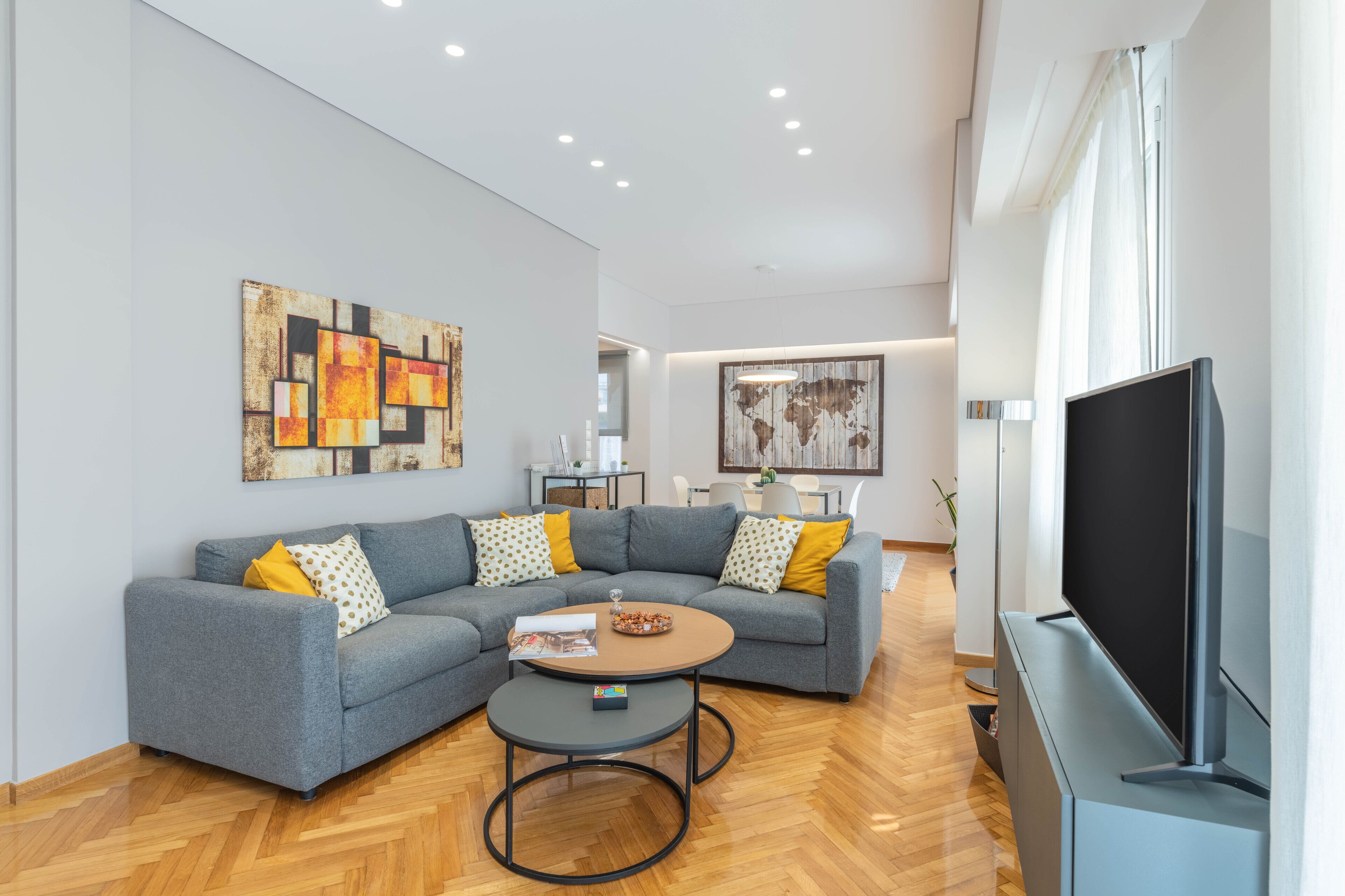 A modern living room with a grey sectional sofa, a coffee table, and a flat-screen TV.