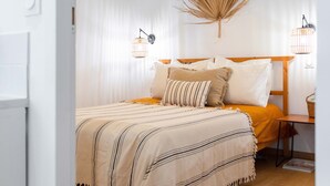 A bedroom with a bed, bedside tables, and a hanging light fixture.