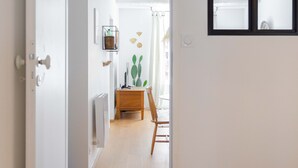 A hallway with a wooden floor, a door on the left, and a window on the right.