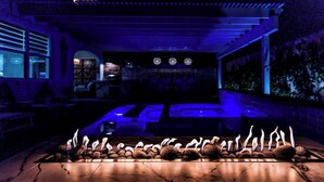 Un espace bar à la lumière tamisée, avec un long comptoir et une rangée de bougies.