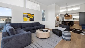 A modern living room with a sectional sofa, a round coffee table, and a dining area with a high table and chairs. - NEW LISTING... Magnificent NEW Townhome, overlooking dt Hood River, garage (Hood River)