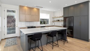 A modern kitchen with a large island, dark cabinetry, and a stainless steel refrigerator. - NEW LISTING... Magnificent NEW Townhome, overlooking dt Hood River, garage (Hood River)
