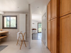 Modern kitchen with a window overlooking lush greenery, featuring a sink, countertop, and wooden cabinet.