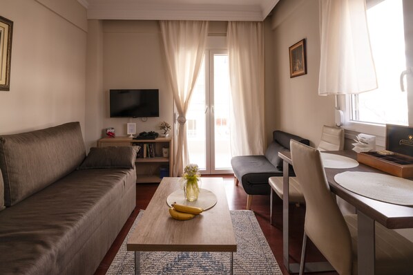 Relax in this stylish living room with a comfortable sofa, flat-screen TV, and dining area.