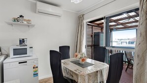 Un coin repas avec une table dressée pour quatre personnes, un four à micro-ondes et un petit réfrigérateur.