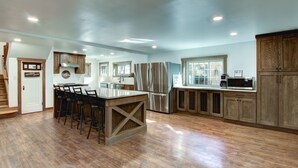 A spacious kitchen with a central island, bar stools, stainless steel appliances, and wooden cabinetry. - Otter Creek Manor - Oversized 3bd, 1.5 Ba. 3 acres, creek access. (Eau Claire)