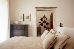 A bedroom with a bed, a dresser, and a wall with hanging items.