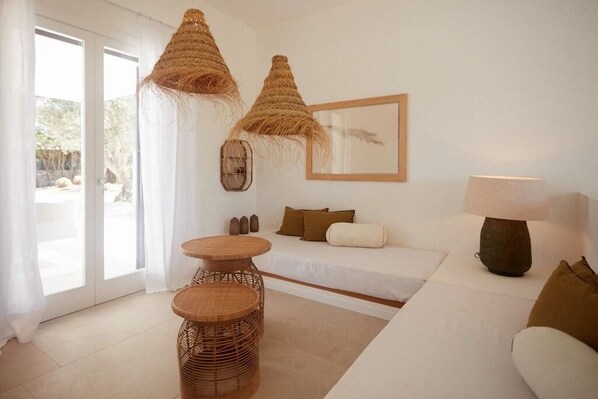 A modern living room with a sofa, two wicker tables, a lamp, and a framed picture on the wall.