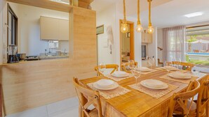 A dining area with a wooden table set for four, surrounded by wooden chairs.