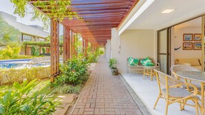 A covered outdoor area with a brick pathway, wicker furniture, and potted plants.